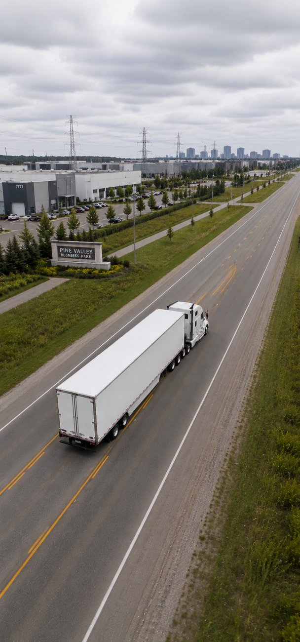 White enclosed transport truck on a Canadian highway by an industrial business park